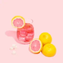 Glass of pink lemonade with lemons surrounding.