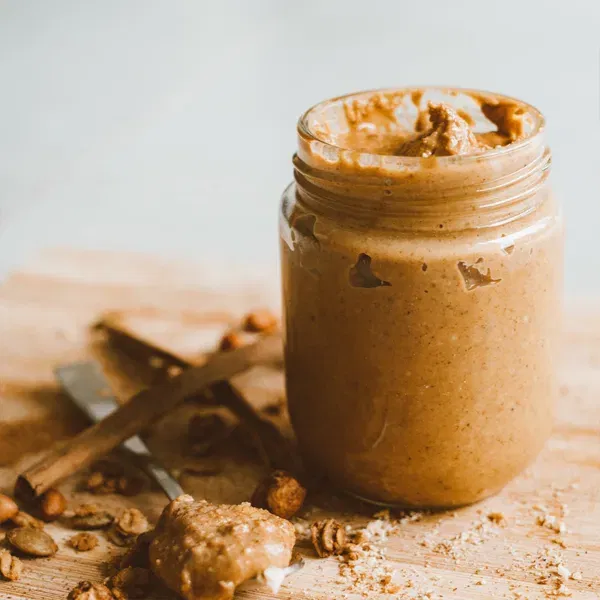jar of peanut butter with peanuts surrounding it