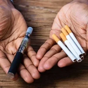 hands holding E-cigarette vs cigarettes.