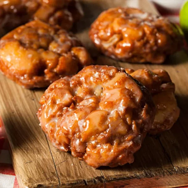 Apple fritter pastries on a wood cutting board.