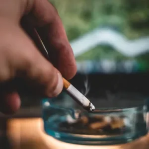 Close up of a hand ashing a cigarette in an ash-tray.